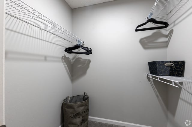 Walk-in closet with wire shelving and laundry hamper.