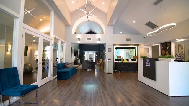 Modern apartment building lobby with a reception desk and seating areas.