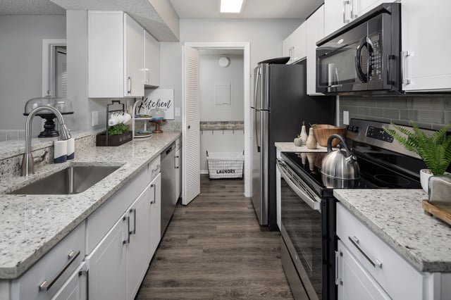 Modern kitchen with granite countertops, stainless steel appliances, and a laundry closet.