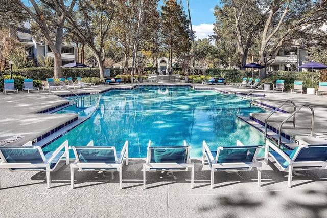 Resort-style swimming pool with lounge chairs and umbrellas.