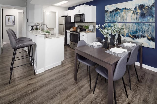 Modern kitchen and dining area with granite countertops, stainless steel appliances, and a dark wood dining table.