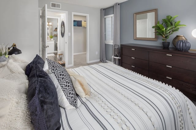 Bedroom with a large bed, dresser, and access to bathroom and closet.