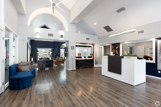 Modern apartment complex lobby with a reception desk, seating area, and arched ceiling.