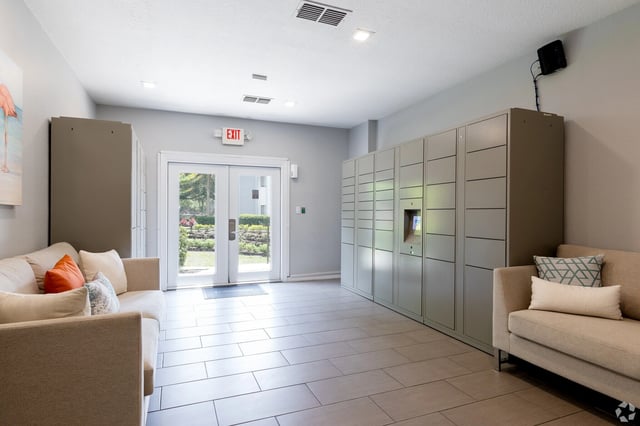 Mailroom with package lockers, seating areas, and a painting of flamingos.