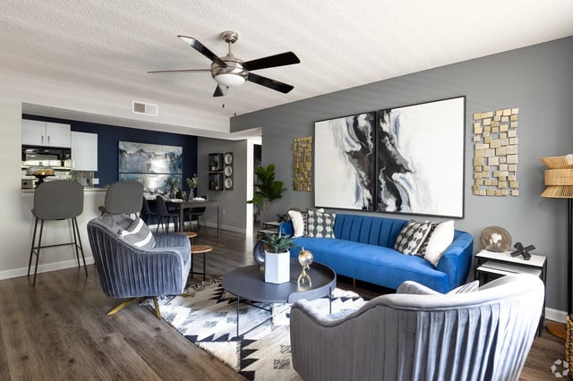 Modern living room with blue sofa and grey armchairs.