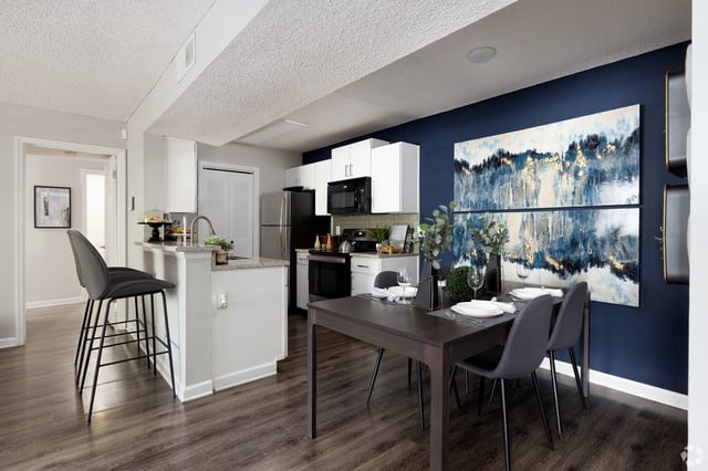 Kitchen and dining area with a breakfast bar, modern chairs, and abstract art.