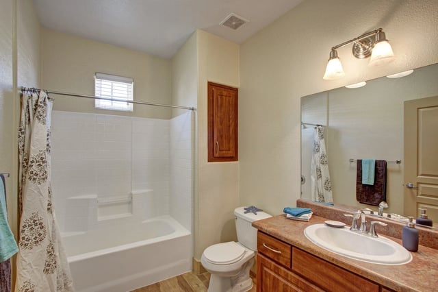 Clean and bright apartment bathroom with a bathtub, shower, toilet, and vanity.