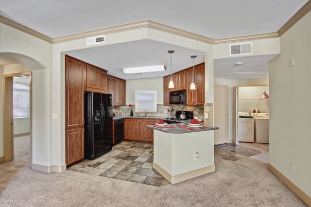 Kitchen and laundry area with wooden cabinets, granite countertops, and stainless steel appliances.
