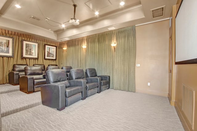 Tiered seating with plush leather chairs and a projector screen in a community media room.