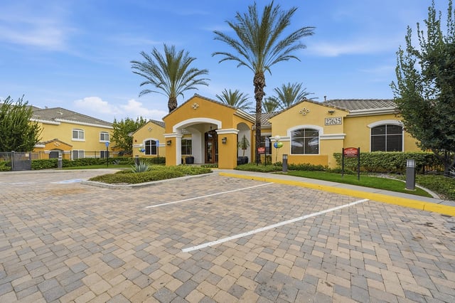 Exterior of the apartment building with palm trees and parking lot.