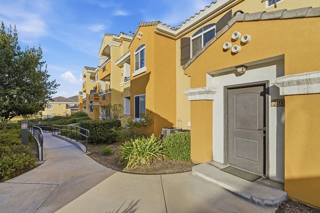Exterior view of apartment buildings with a walkway and landscaping.
