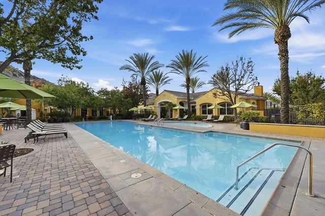 Resort-style swimming pool with lounge chairs and umbrellas.