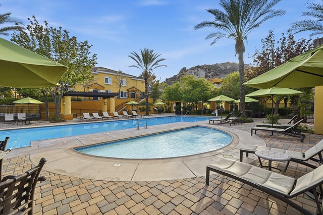Resort-style swimming pool with lounge chairs and umbrellas.
