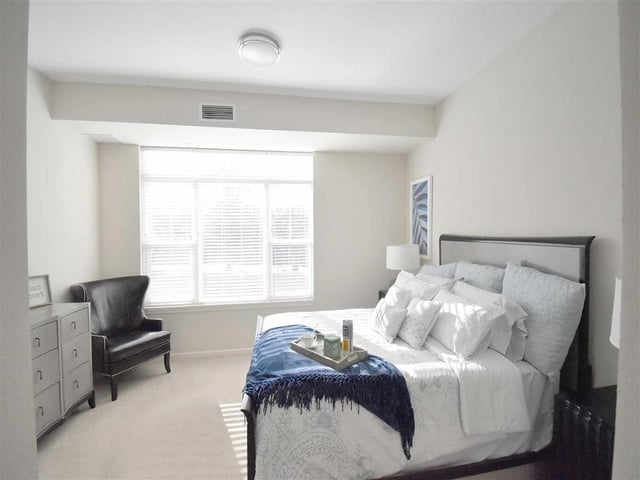 Bright bedroom with a large window, king-size bed, and a comfortable armchair.