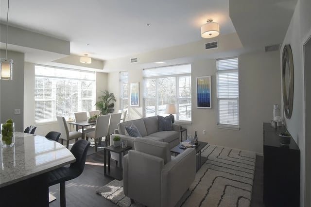 Living room and dining area with sofa, chairs, dining table, and large windows.