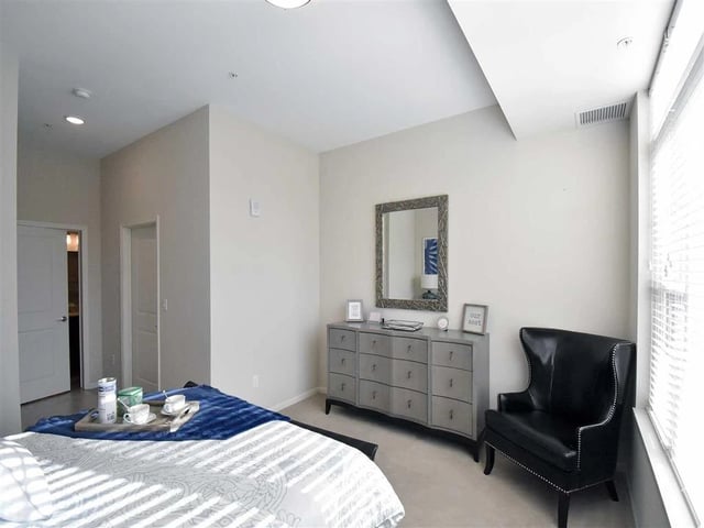 Bedroom with a bed, dresser, mirror, and armchair.