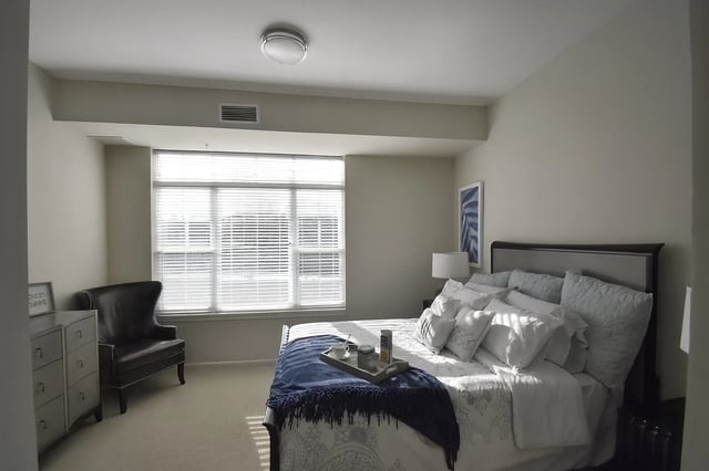 Bedroom with a king-size bed, dresser, and armchair.