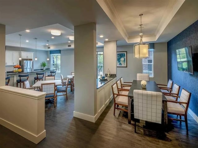 Dining area with tables and chairs next to a kitchen counter with bar stools.