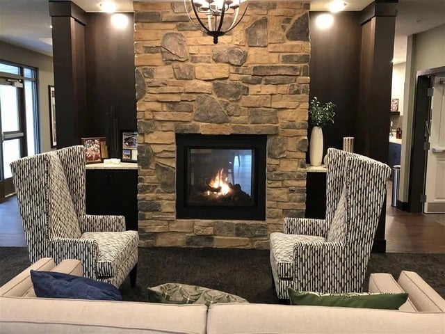 Cozy seating area with a stone fireplace and two wingback chairs.
