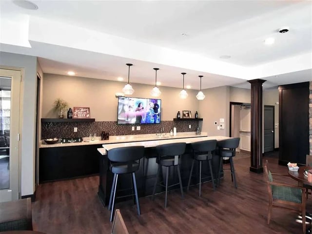 Community lounge area with a wet bar, bar stools, and a TV.