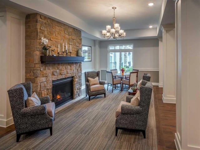 A cozy seating area with a stone fireplace, comfortable armchairs, and a small dining table.