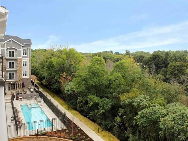 Outdoor swimming pool and patio area next to a wooded area.