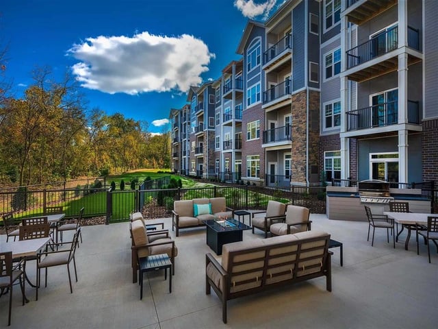 Luxury apartment building exterior with outdoor seating and grilling area.