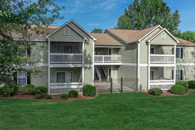Exterior view of apartment building with balconies and green lawn.