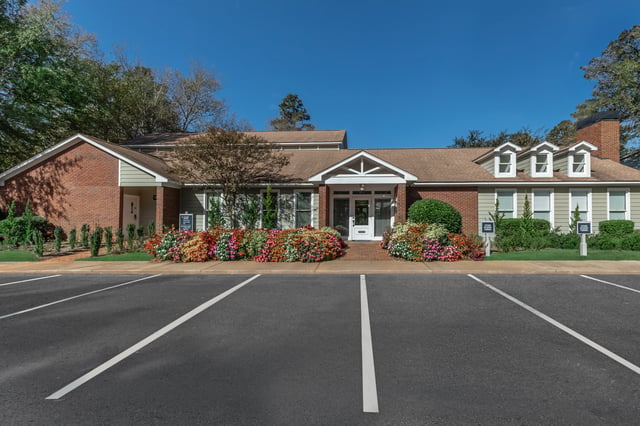 Exterior view of the apartment building entrance with colorful flower beds.