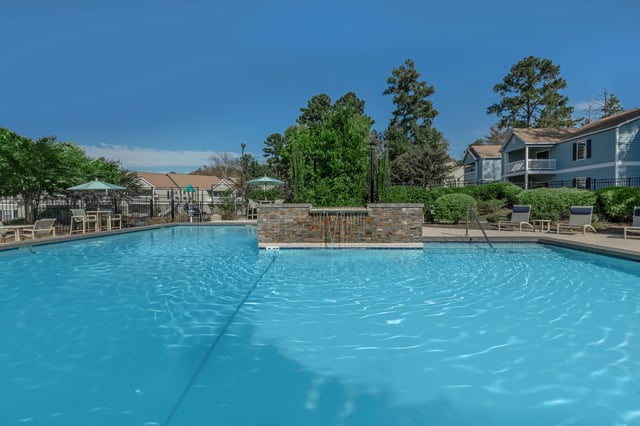 Outdoor swimming pool with lounge chairs and a waterfall feature.