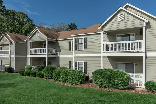Exterior view of apartment buildings with balconies and manicured landscaping.