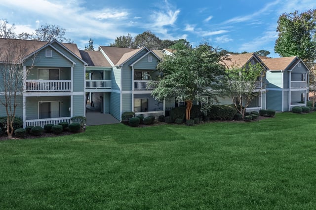 Exterior view of apartment buildings with blue siding and white balconies.
