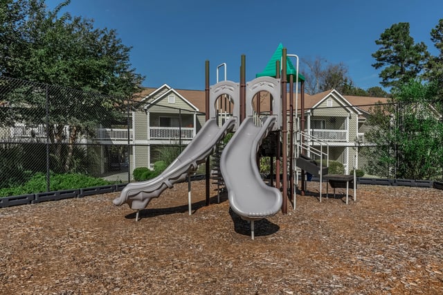 Playground with slides and apartment buildings in the background.