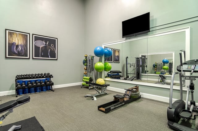 Fitness center with weight rack, exercise balls, rowing machine, and elliptical.
