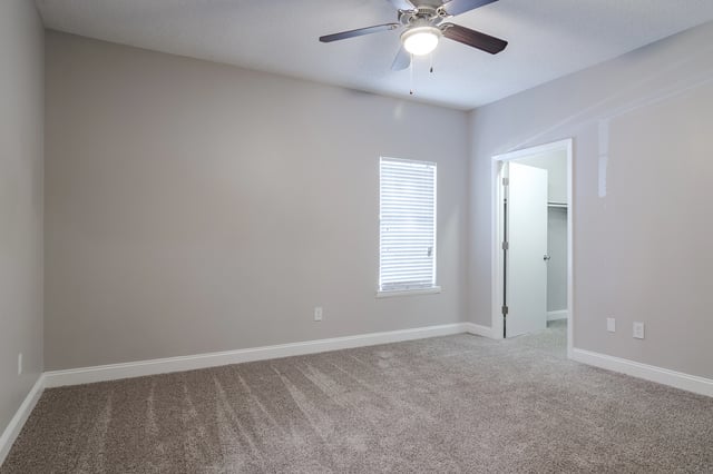 Empty bedroom with carpet, a ceiling fan, and a closet.