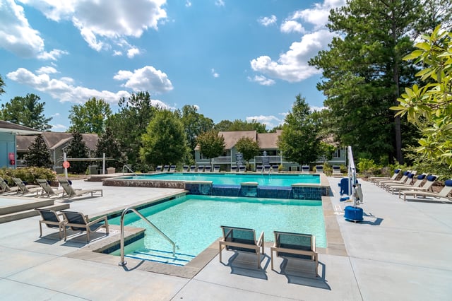 Resort-style swimming pool with lounge chairs and umbrellas