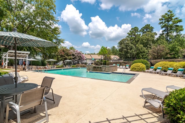 Resort-style swimming pool with lounge chairs and umbrellas
