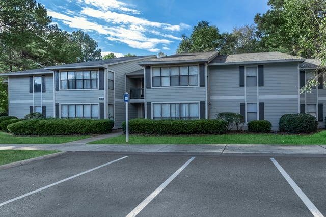 Exterior view of apartment buildings with manicured landscaping and parking lot.