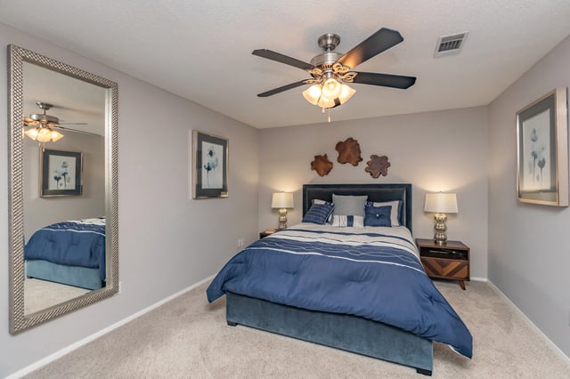 Bedroom with a queen-size bed, dresser, and large mirror.