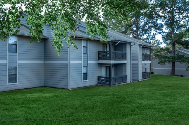 Exterior view of apartment buildings with balconies and green lawn.