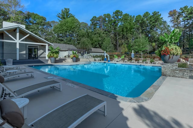 Outdoor swimming pool with lounge chairs and a building in the background.