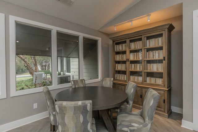 Round dining table with chairs in a common area with a large bookcase.