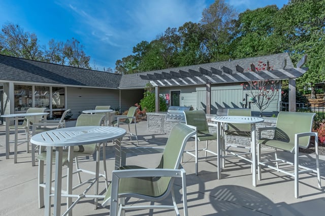 Outdoor patio area with high-top tables, chairs, and built-in grills under a pergola.