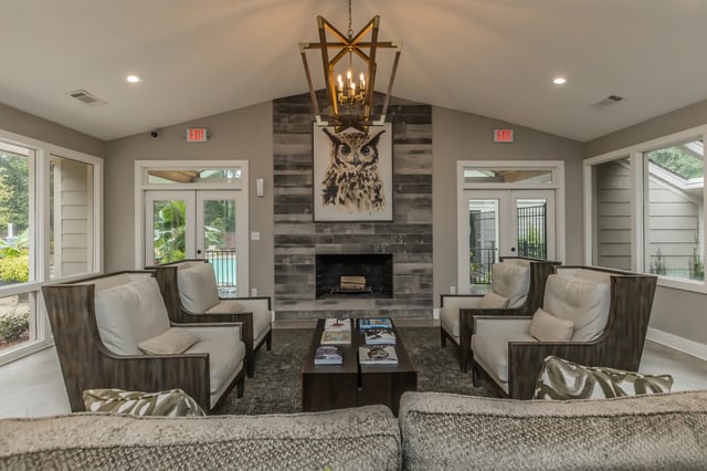 Community lounge with fireplace, seating, and pool view.