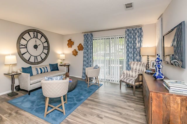 Living room with a large clock on the wall, a sofa, and accent chairs.