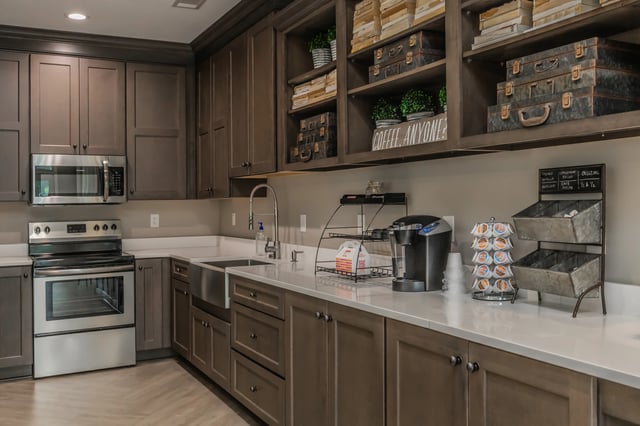 Modern kitchen with dark cabinetry, stainless steel appliances, and a coffee station.