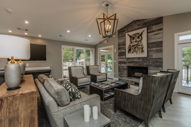 Luxurious community lounge with fireplace, comfortable seating, and view of the pool area.