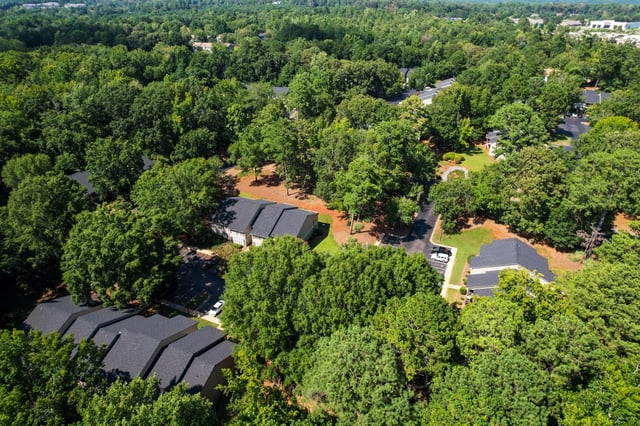 Aerial view of apartment buildings surrounded by lush green trees.