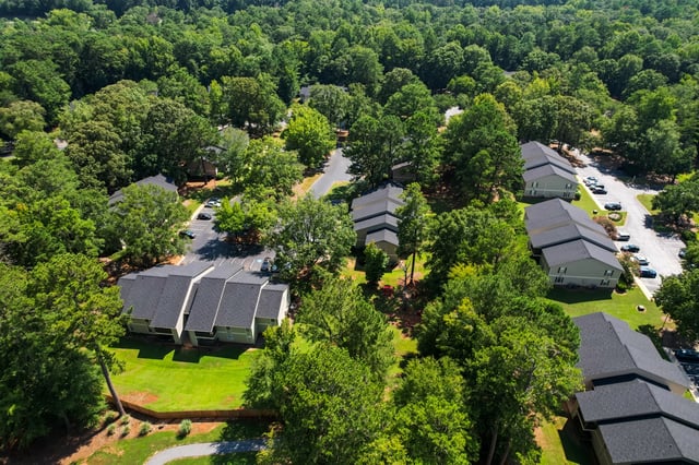 Aerial view of apartment buildings nestled among lush green trees.