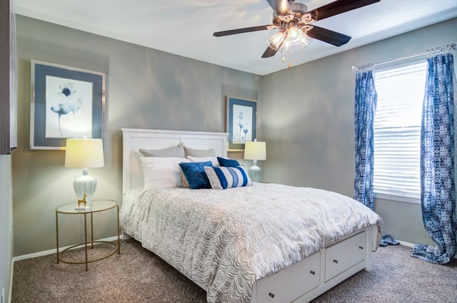 Bedroom with a queen-size bed, ceiling fan, and blue curtains.